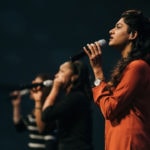 Three women singing on stage