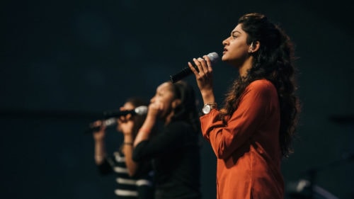 Three women singing on stage