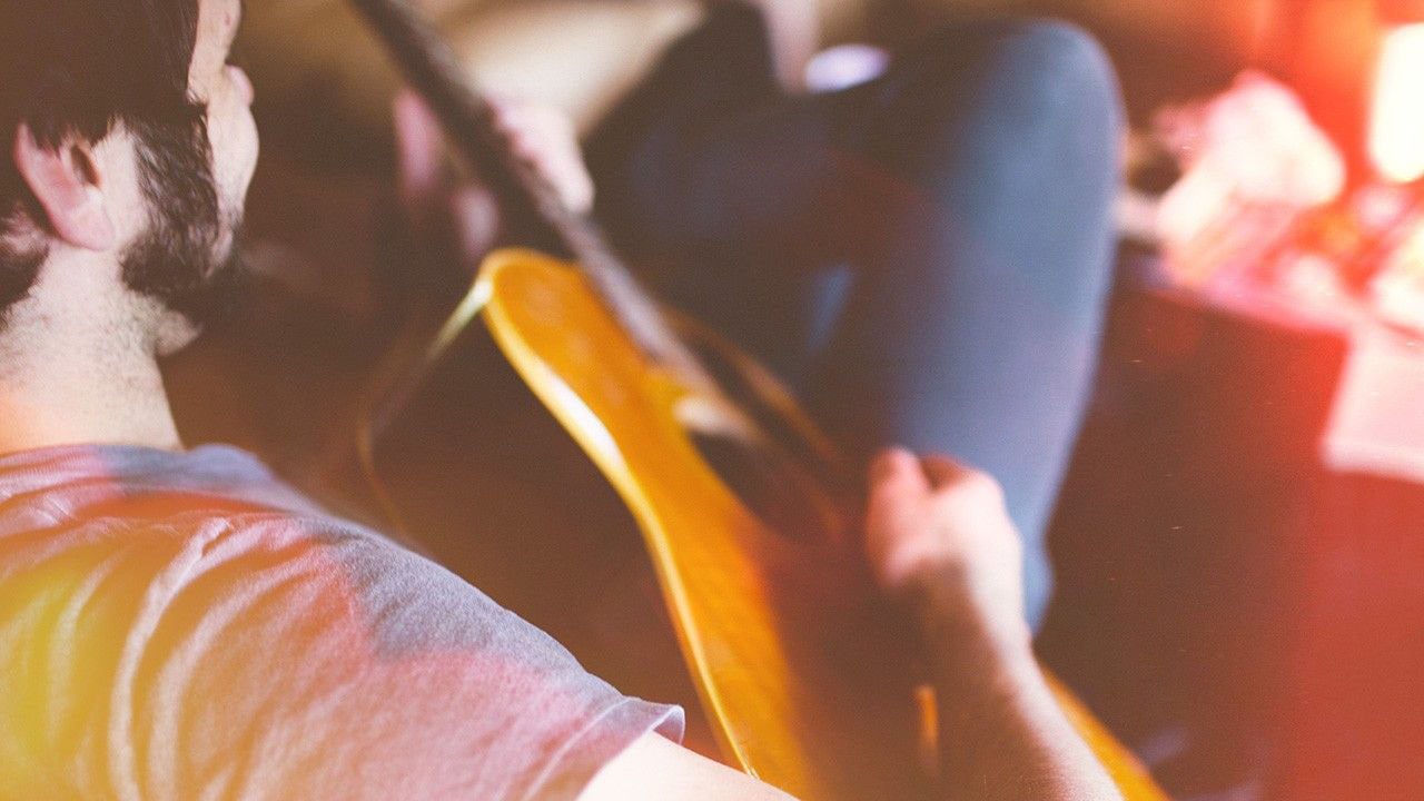 Man reclining and playing acoustic guitar